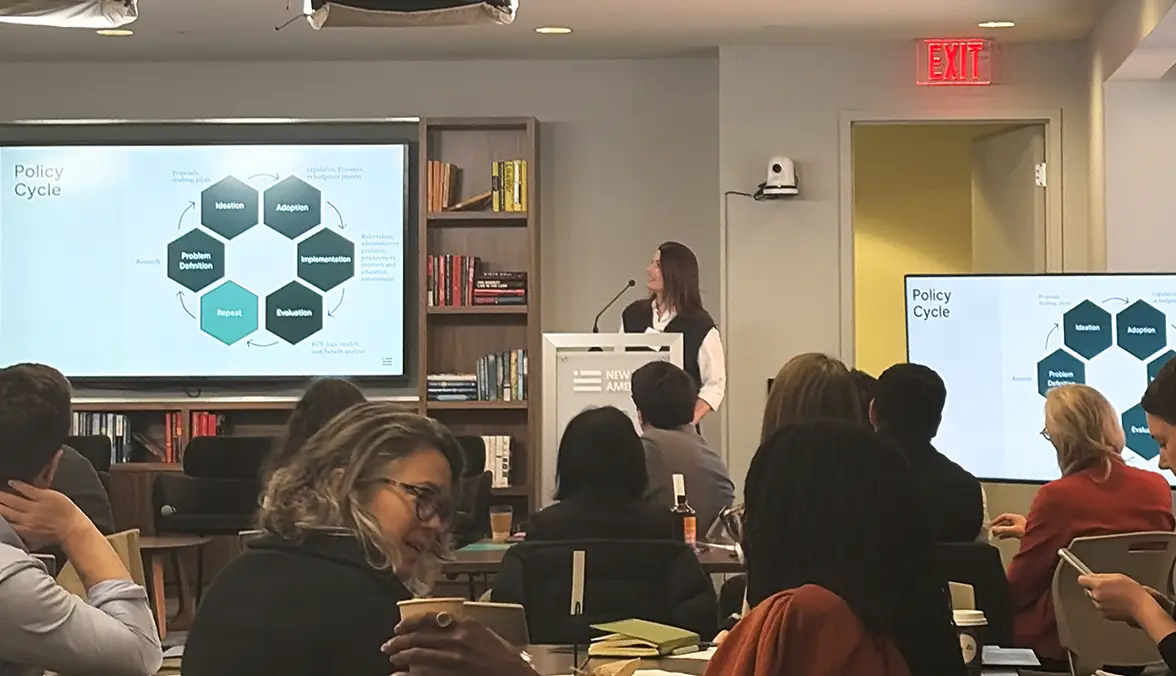 Classroom view of a woman standing at a podium and leading a discussion.